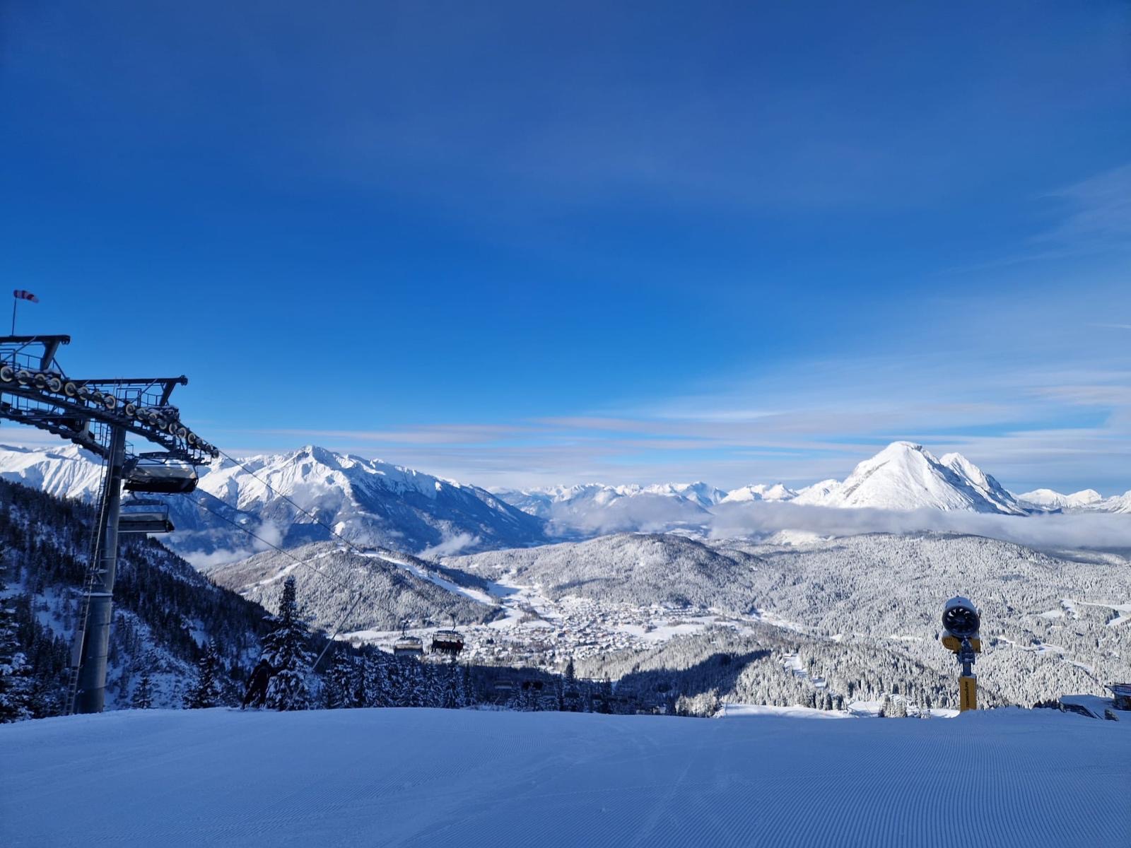 Verschneite Berglandschaft der Olympiaregion Seefeld, im Vordergrund eine frisch präparierte Piste und ein Sessellift.